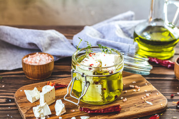 Feta cheese marinated in olive oil with fresh herbs in glass jar
