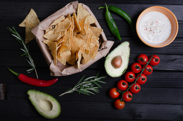 Mexican nachos with sauces on dark background