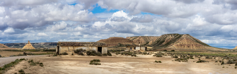 Fototapeta na wymiar Panorama sur la route d'un désert avec deux cabanes abandonnées