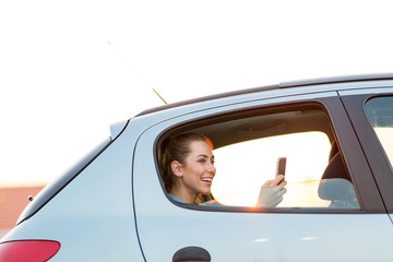 Young woman with smartphone on the back seat of a car