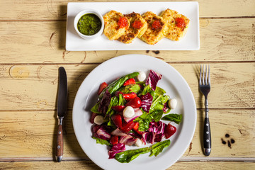 salad of lettuce, red cabbage, mozzarella, strawberry and potato pancakes with red caviar, pesto