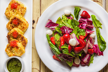 salad of lettuce, red cabbage, mozzarella, strawberry and potato pancakes with red caviar, pesto