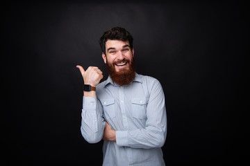 Photo of bearded man showing thumb up and smiling at camera over dark isolated bcakground