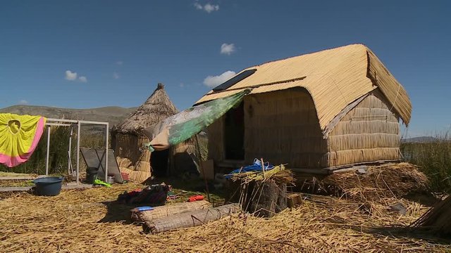 Medium low-angle still shot of a traditional Uros floating  reed huts, and compound, Uros Island, Peru