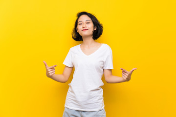 Asian young woman over isolated yellow wall proud and self-satisfied