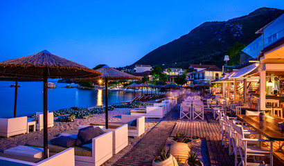 Romantic scene on Nikiana beach in evening lights with illuminated terrace on the seaside in Lefkada island of Greece