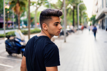 Young fashionable handsome man on the street of modern city. He looks happy