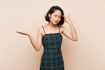 Asian young woman over isolated yellow wall making the gesture of madness putting finger on the head