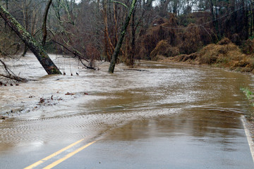 Surging River Overflows Its Banks and Swamps a Road