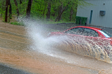 Car Plows Into Water On a River Flooded Road
