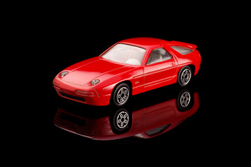 Red modern die-cast model car on the black reflective background