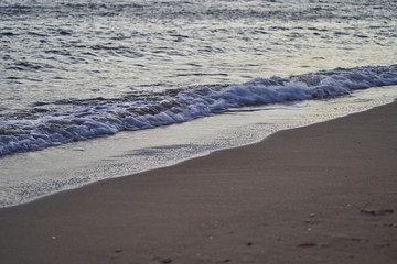 Sandy coast with sea waves at sunrise.
