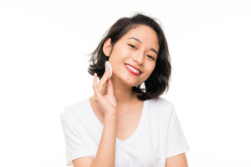 Asian young woman removing makeup from her face with cotton pad