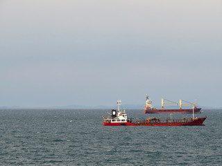 Two cargo ships at anchor on the sky and sea background with empty space for your text
