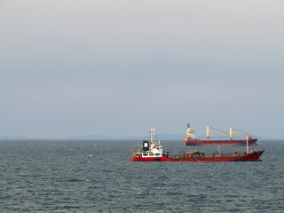 Fototapeta premium Two cargo ships at anchor on the sky and sea background with empty space for your text