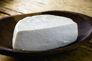 minced cheese cut in half on wooden table. Typical cheese made in Brazil in the state of minas gerais and used in desserts.