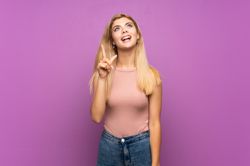 Teenager girl over isolated purple background pointing up and surprised