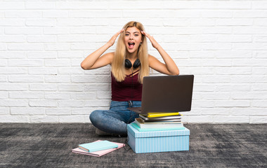 Teenager girl sitting on the floor with her laptop with surprise expression