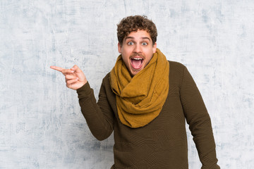 Naklejka premium Blonde man over grunge wall surprised and pointing finger to the side