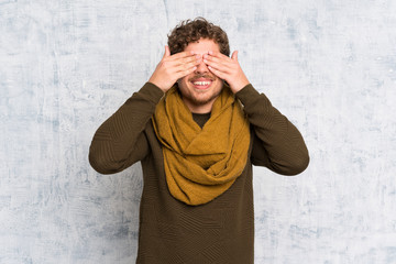 Blonde man over grunge wall covering eyes by hands