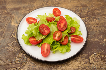plate of salad with cherry tomatoes and lettuce. dressing with olive oil. Dietary food