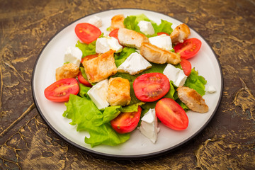 Warm salad with chicken, cherry tomatoes and soft cheese cheese. dressing with olive oil. Dietary meal