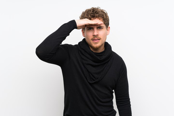 Fototapeta premium Blonde man over isolated white wall looking far away with hand to look something