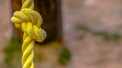 Panorama Close up view of a knotted yellow rope with dirt on the surface