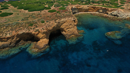 Aerial view of small islet of Ydrousa with turquoise and sapphire clear waters and only one mile distance from coast in Voula, Athens riviera, Attica, Greece