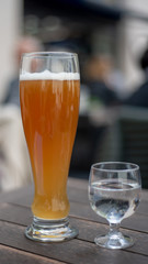 Wheat beer on table with cup of water viewed from the side outdoors