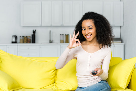 happy african american woman with remote controller showing ok sign