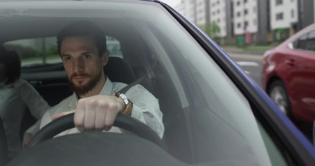 Male uber driver talks to his passenger inside the car