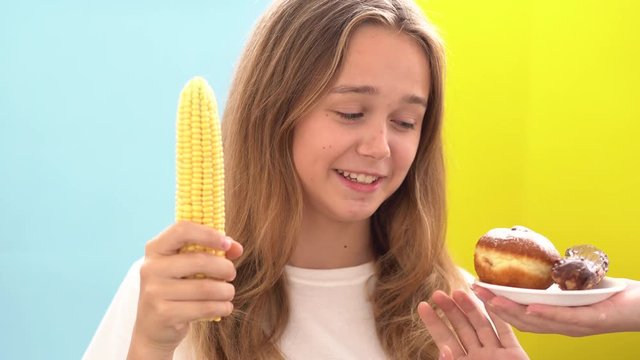 Concept of healthy and unhealthy food.Beautiful woman face choice food. Healthy natural vegetables or sweet dessert concept. Healthy vs junk food