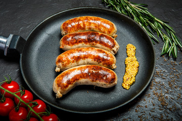 round pan with four fried sausages and granular mustard