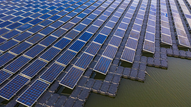 Solar panels in aerial view, rows array of polycrystalline silicon solar cells or photovoltaics in solar power plant floating on the water in lake.