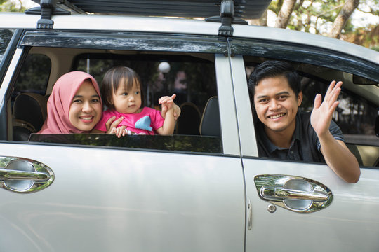 Young Muslim Family , Transport, Leisure, Road Trip And People Concept - Side View Of Happy Man, Woman And Little Girl  Ready For Traveling Inside A Car Looking Out Windows At Sunny Day