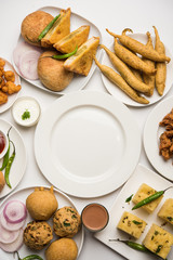 Indian Tea time snacks  in group includes Veg Samosa, Kachori/kachaudi, aloo bonda, khaman dhokla, bread, onion,chilli and moong pakora/pakoda/bhaji/bhajji/Bhajiya/bajji with sauces, selective focus