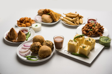 Indian Tea time snacks  in group includes Veg Samosa, Kachori/kachaudi, aloo bonda, khaman dhokla, bread, onion,chilli and moong pakora/pakoda/bhaji/bhajji/Bhajiya/bajji with sauces, selective focus