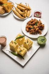 Indian Tea time snacks  in group includes Veg Samosa, Kachori/kachaudi, aloo bonda, khaman dhokla, bread, onion,chilli and moong pakora/pakoda/bhaji/bhajji/Bhajiya/bajji with sauces, selective focus