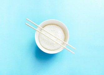 Traditional Bowl of rice and chopsticks isolated on blue. Asian cuisine.Healthy food concept.top view, flat lay.