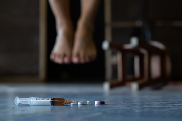 Syringe and drugs with out of focus The foot of the person commit suicide.Depression.International Day against Drug Abuse and Illicit Trafficking