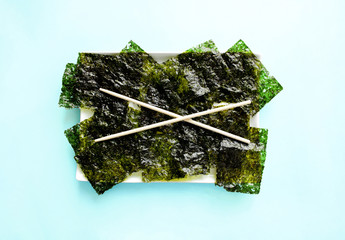 Crispy  Dried seaweed and chopsticks on a plate, top view. Asian cuisine. Food background with copy space.