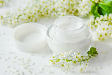 Fototapeta na wymiar White beauty cream with white flowers on white background.Cosmetic cream -top view. Moisturizing face cream for spa treatment. Beauty background with facial cosmetic product. flat lay. 