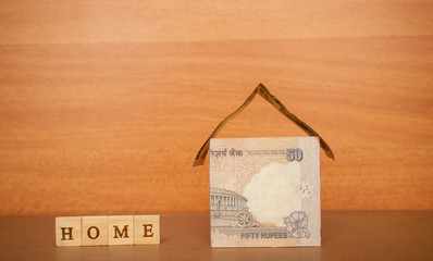 House made from the Indian currency notes and Home Loan in wooden block letters on wooden background