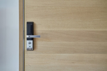 Digital door knob or electronic door handle on wooden door. Selective focus.