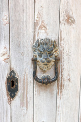 Very old wooden door with rusty vintage door lion head handle and keyhole, Valletta, Malta