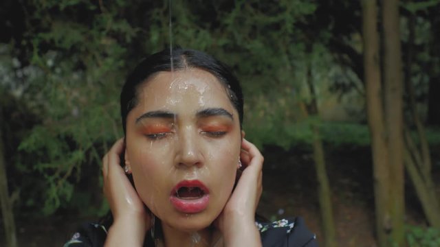 portrait of a beautiful brunette girl with makeup. a jet of water pours sexually on the girl's face from above. 4k. 4k video