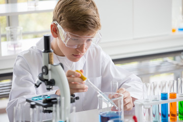 Pupils in white gown doing a chemical experiment in laboratory at school .kids in science lab study using pipette dropping liquid to test tube  , caucasian , biochemistry . chemistry class