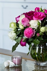 Female Interior - bouquet of fragrant pink and white English roses, shells and pink candle on the glass table