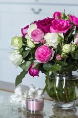 Female Interior - bouquet of fragrant pink and white English roses, shells and pink candle on the glass table